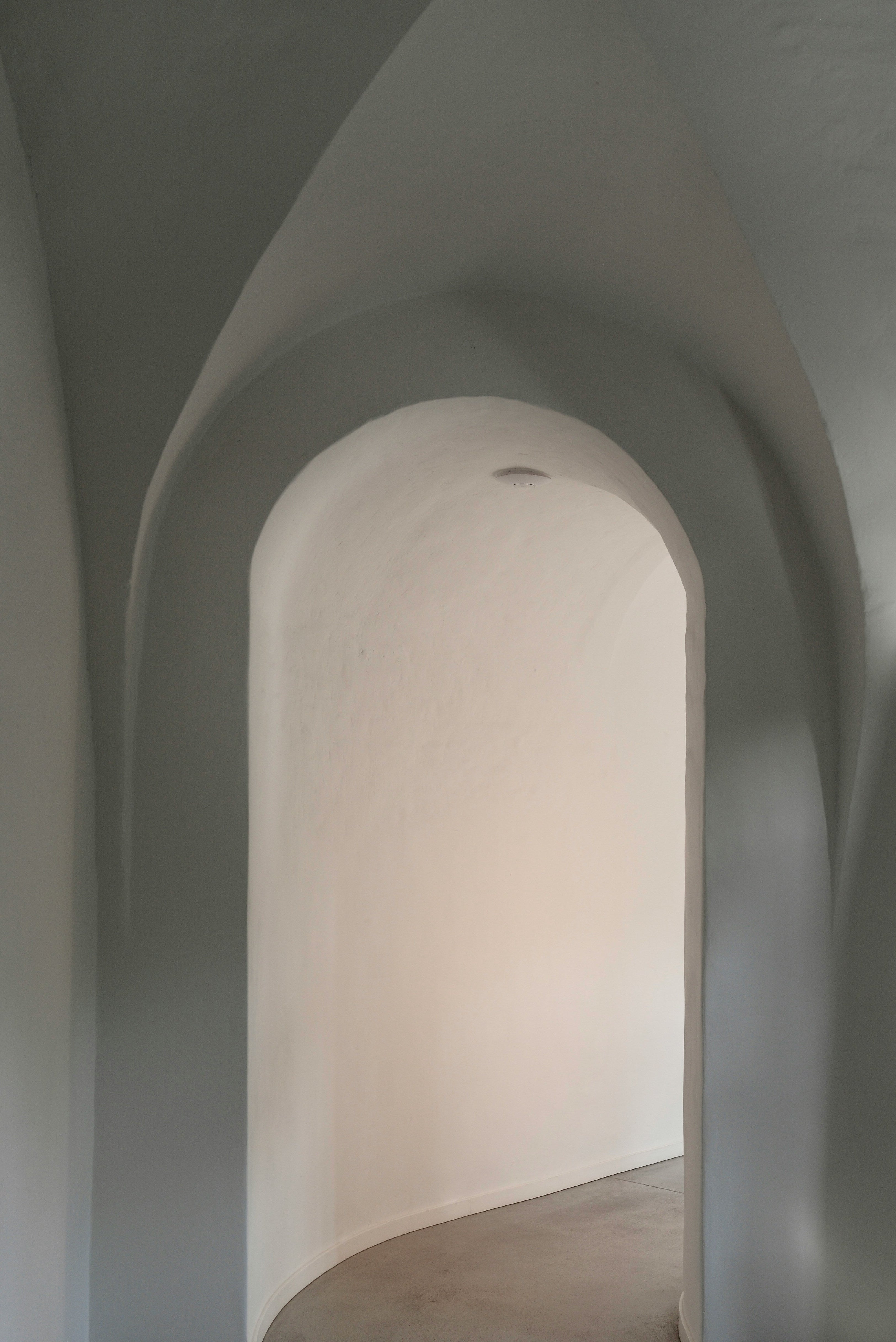 Architectural interior with curved walls and a light source at the end